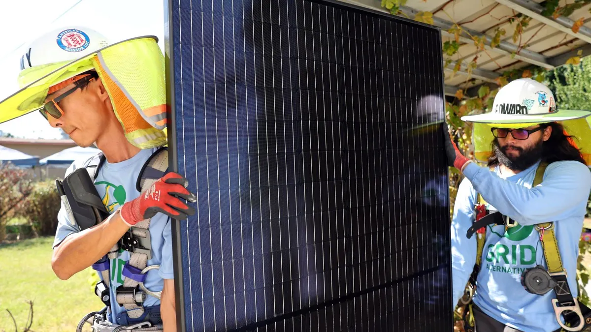 Picture shows solar installers carrying a panel.