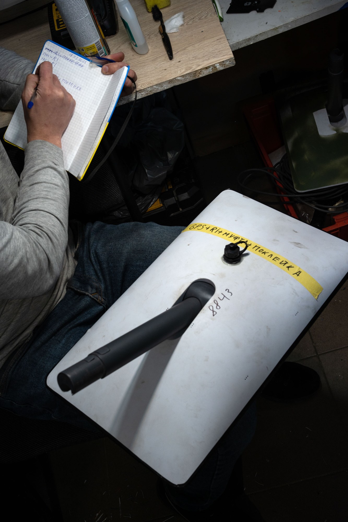 close up of a Starlink unit on the lap of a volunteer, who is writing notes in a gridded notebook