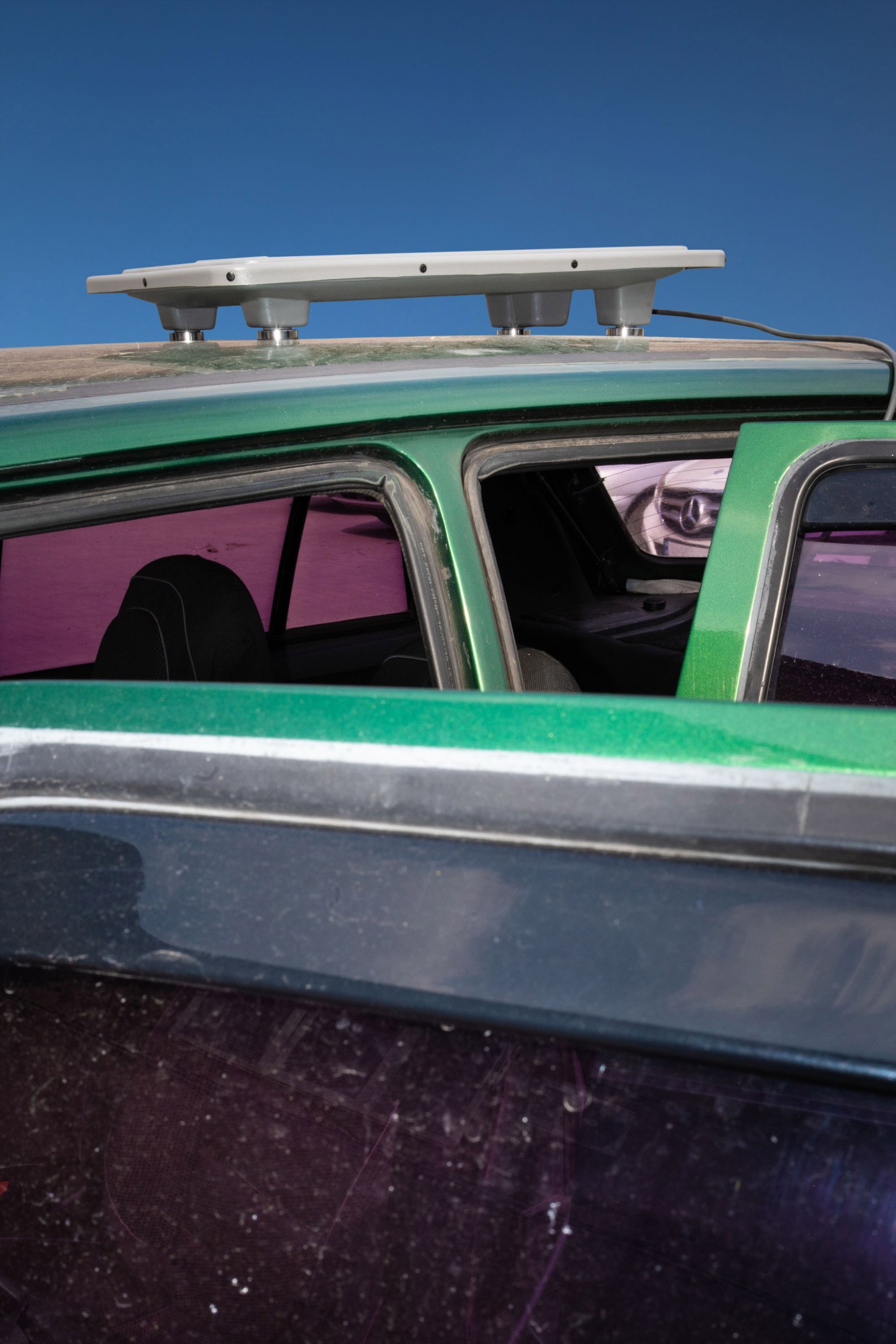 a Starlink unit mounted to the roof of a vehicle with pink tinted windows