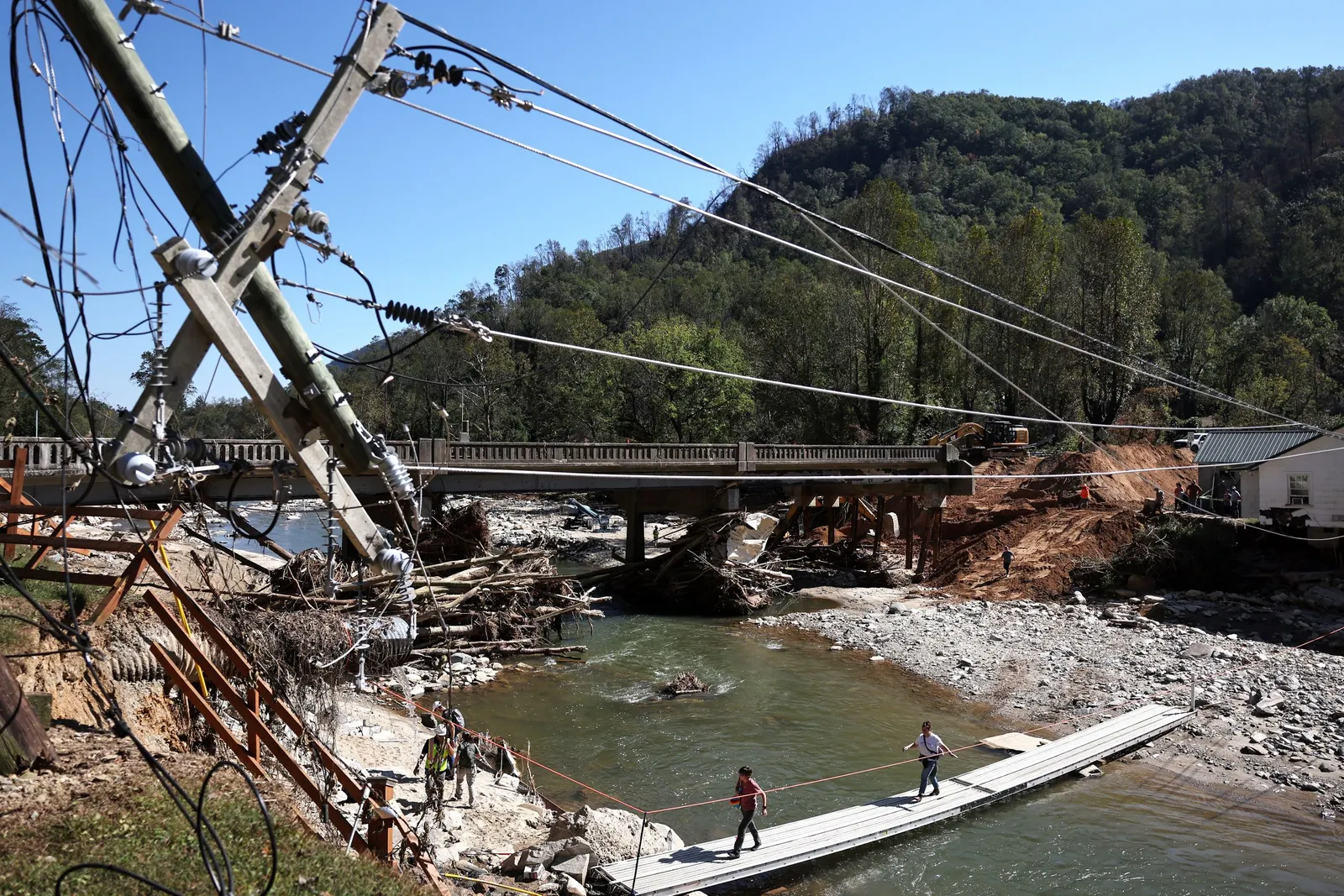 People walk across a makeshift bridge as a damaged bridge is repaired.
