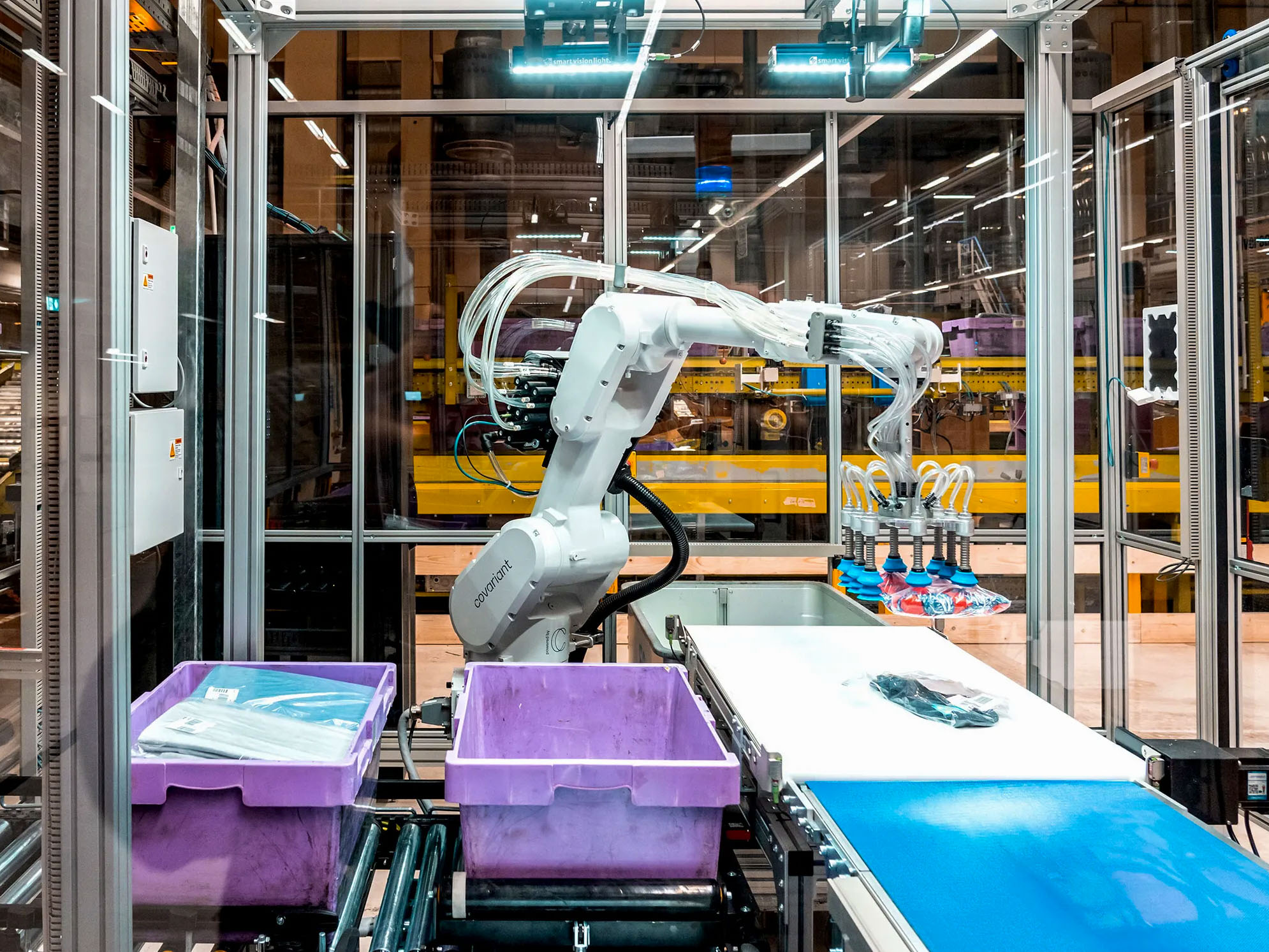 a warehouse robot arm lifts object with many suckers to place in a bin