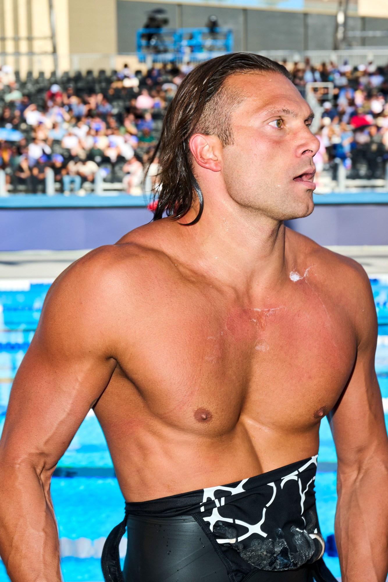 Cody Miller standing by the pool in profile