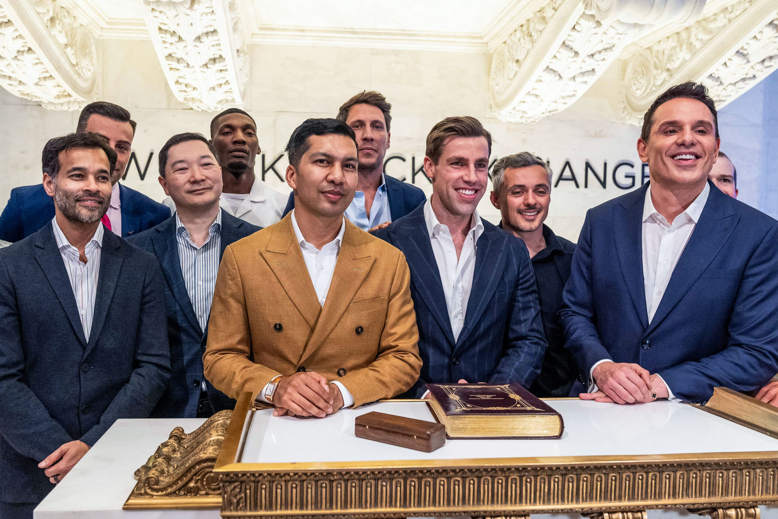 a group of men in business suits posing at the desk of the NYSE