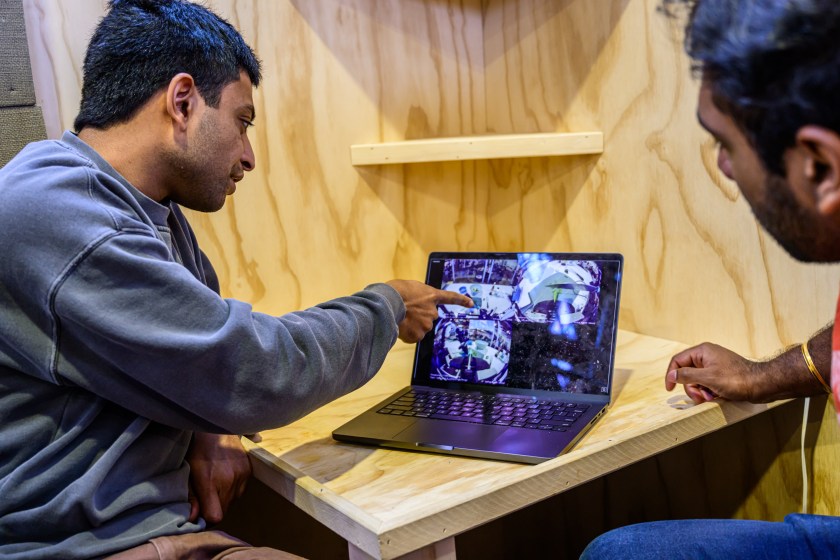 A researcher points out a detail from a training video to his colleague on a laptop screen